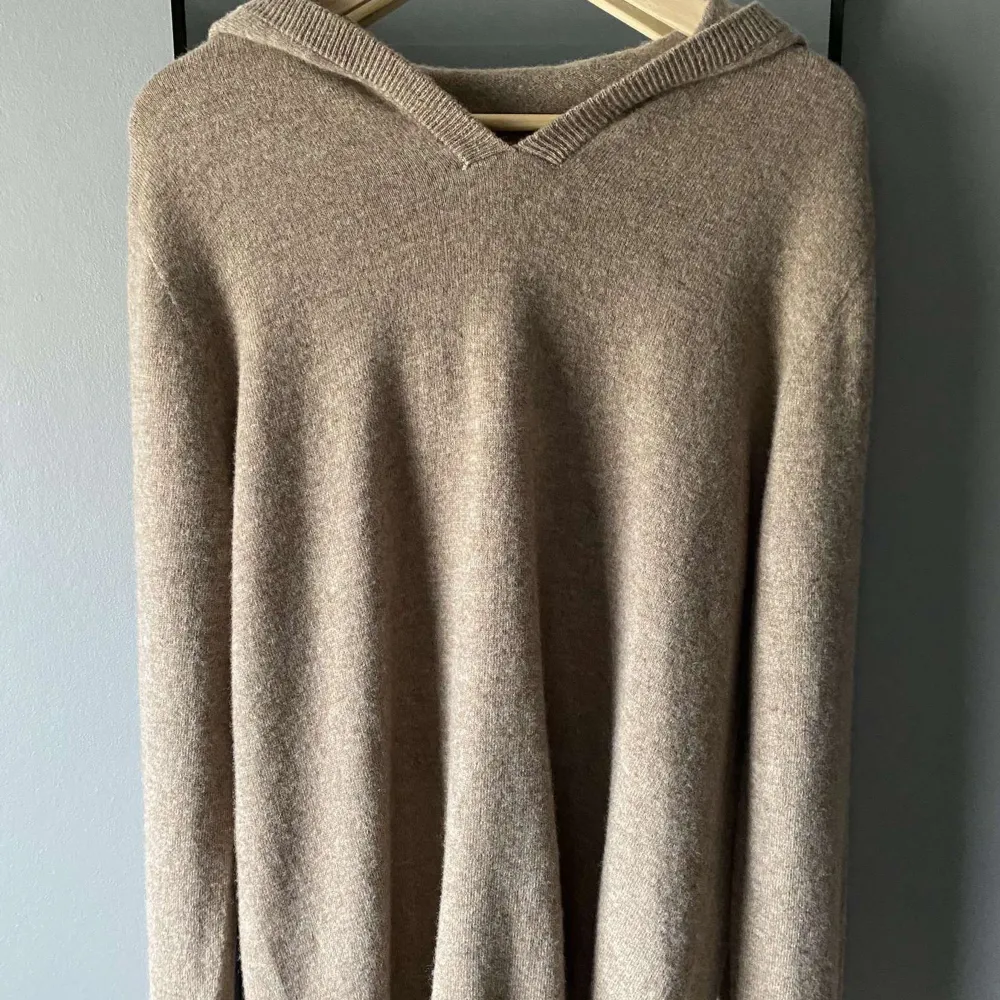 Säljer en supermysig beige stickad cashmere hoodie. Perfekt för höst och vinter med sin varma och mjuka känsla. Den har en snygg v-ringad design och långa ärmar. Passar perfekt för en avslappnad stil!. Tröjor & Koftor.