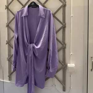 Klänning shein - Lila klänning med långa ärmar och en knytning i midjan. Blusen har en V-ringning och en klassisk krage. Den är använd 2 gånger och är från Shein! 