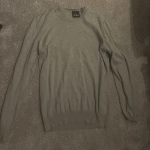 Grå tröja från Oscar Jacobsson  - Säljer en stilren och enkel grå tröja från Oscar Jacobsson. Den är långärmad och perfekt för både vardag och lite finare tillfällen. Tröjan är i bra skick och har en normal passform. Perfekt för höst och vinter!