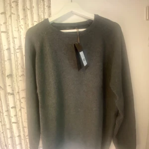 Grå tröja från Oscar Jacobson - Säljer en stilren och klassisk grå tröja från OJ. Den har en rund hals och är perfekt för både vardag och lite finare tillfällen, den är därtill oanvänd. Ber om ursäkt för kamerakvaliten, därav en bild från OJ hemsida som komplement.