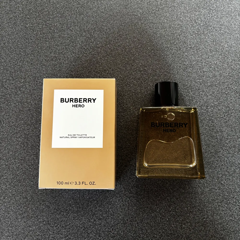 Säljer en elegant och stilren Burberry Hero Eau de Toilette. Flaskan rymmer 100 ml. Doften är fräsch och maskulin, perfekt för dagligt bruk eller speciella tillfällen. Kommer i en snygg beige kartong. Oanvänd, endast tagit ett sprut. Nypris: 1465 kr.. Parfym.