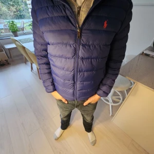 Blå dunjacka från Ralph Lauren - Säljer en snygg blå dunjacka från Ralph Lauren. Den är superpraktisk eftersom den är packbar och lätt att ta med sig.Perfekt för hösten storlek S