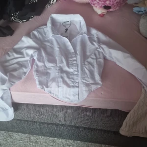 Vit croppad skjorta från Noisy May - Säljer en superfin vit croppad skjorta från Noisy May. Den har långa ärmar och knappar framtill. Perfekt för både vardag och fest! 💫