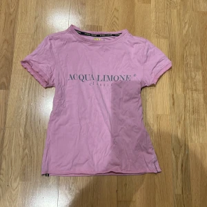 Rosa t-shirt från Acqua Limone - Säljer en rosa t-shirt från Acqua Limone med tryck både fram och bak. T-shirten har korta ärmar och en rund halsringning. Perfekt för en avslappnad stil.