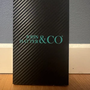 Mobilskal från John Hatter & Co - Snyggt mobilskal från John Hatter & Co med texten 'Work Hard Play Harder'. Skalet har ett coolt mönster i grått och svart och är perfekt för att skydda din telefon med stil. Passar perfekt för den som vill ha en kombination av funktion och design. Den passar IPhone 14 PRO. Aldrig använt pga för litet. Pris går att diskutera.