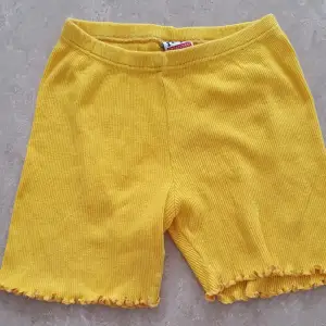 Säljer ett par supergulliga gula ribbade shorts från H&M i storlek 116. De har en elastisk midja och söta volangdetaljer vid bensluten. Perfekta för sommarens lek och äventyr!