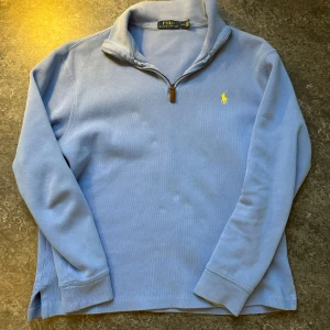 Ljusblå tröja från Polo Ralph Lauren - Säljer en snygg ljusblå tröja från Polo Ralph Lauren i storlek S. Den har en dragkedja vid halsen och det klassiska broderade logotypen i gult på bröstet. Perfekt för både vardag och lite finare tillfällen. Tröjan är i bra skick och passar perfekt till hösten och vinter. Nypris ligger på 1950. 