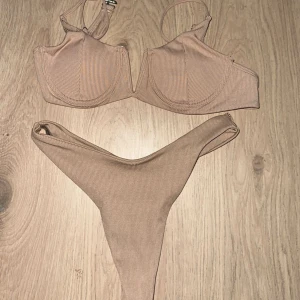 Beige ribbad bikini - Säljer en superfin beige ribbad bikini i mycket bra skick. Toppen har en stilren design med breda axelband och en v-ringad skärning. Bikinitrosorna har en hög midja som ger en snygg passform. Perfekt för sommarens stranddagar eller poolhäng! 🏖️