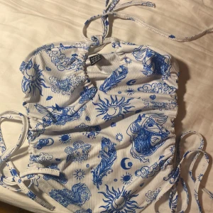 topp med gulligt mönster - säljer en superfin vit och blå topp. den har knytband i nacken och vid sidorna, så man kan justera den hur man vill🫶🏻den går dessutom att knyta på lite olika sätt!❤️skriv om du har några frågor!!