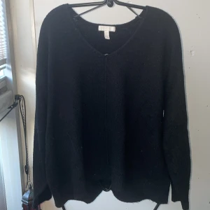 Svart tröja från H&M - Säljer en klassisk svart tröja från H&M st. L passar en M. Tröjan har en v-ringad hals och långa ärmar, perfekt för kyligare dagar. Enkel och stilren design som passar till det mesta.