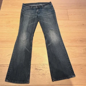 Lågmidjade bootcut jeans - Säljer ett par snygga blå bootcut jeans i bra skick. De har en klassisk femficksdesign och en skön passform. Har cool design vid midjan❤️