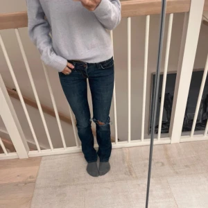 Lågmidjade jeans - Lågmidjade mörkblå jeans med hål i knäna, rak passform i storlek 25/32