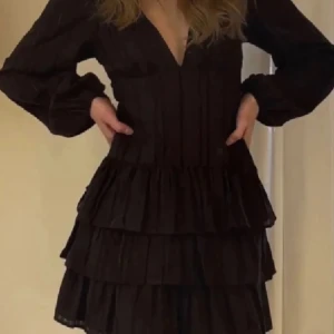 Svart volangklänning - Snygg svart kortklänning med volanger och v-ringning. Perfekt för festliga tillfällen! Är endast använd en gång 