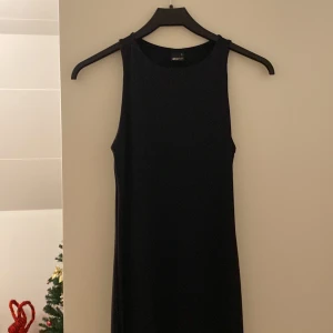 Svart lång klänning från Gina Tricot - Snygg svart lång klänning från Gina Tricot i storlek S. Den är ärmlös och har en enkel, stilren design som passar perfekt för både vardag och fest. Klänningen är i mycket bra skick! Den är endast provad en gång!💕