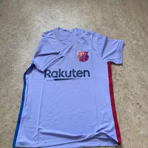 Säljer två Barcelona fotbollströjor i mycket bra skick. Den första är ljuslila med Rakuten-logga och röd-blå ränder på sidorna. Den andra är klassiskt randig i rött och blått med Spotify-logga. Båda har korta ärmar och är perfekta för fans! 💙❤️