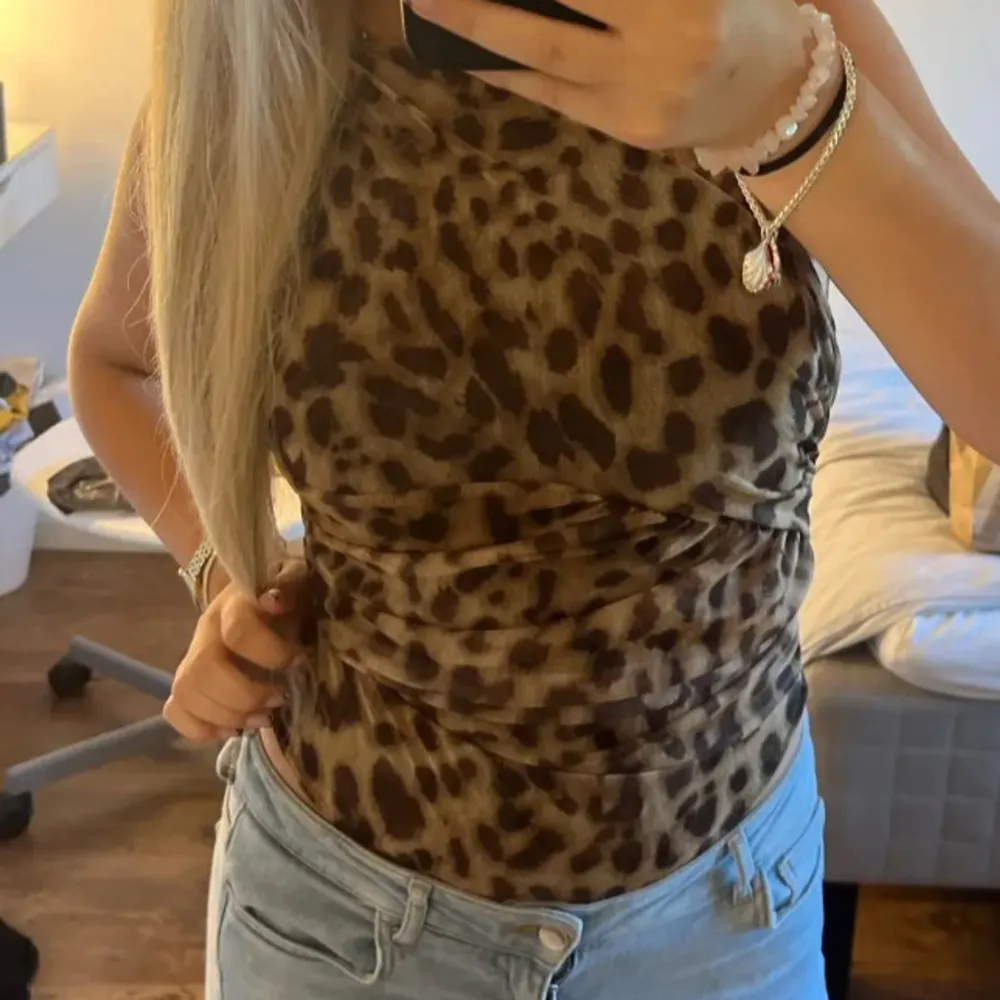 Säljer en snygg leopardmönstrad ärmlös topp som är perfekt för en utekväll eller fest. Toppen har en tight passform och är gjord i ett mjukt och stretchigt material. Den är supertrendig och lätt att matcha med jeans eller kjol för en cool look. 🐆✨. Toppar.