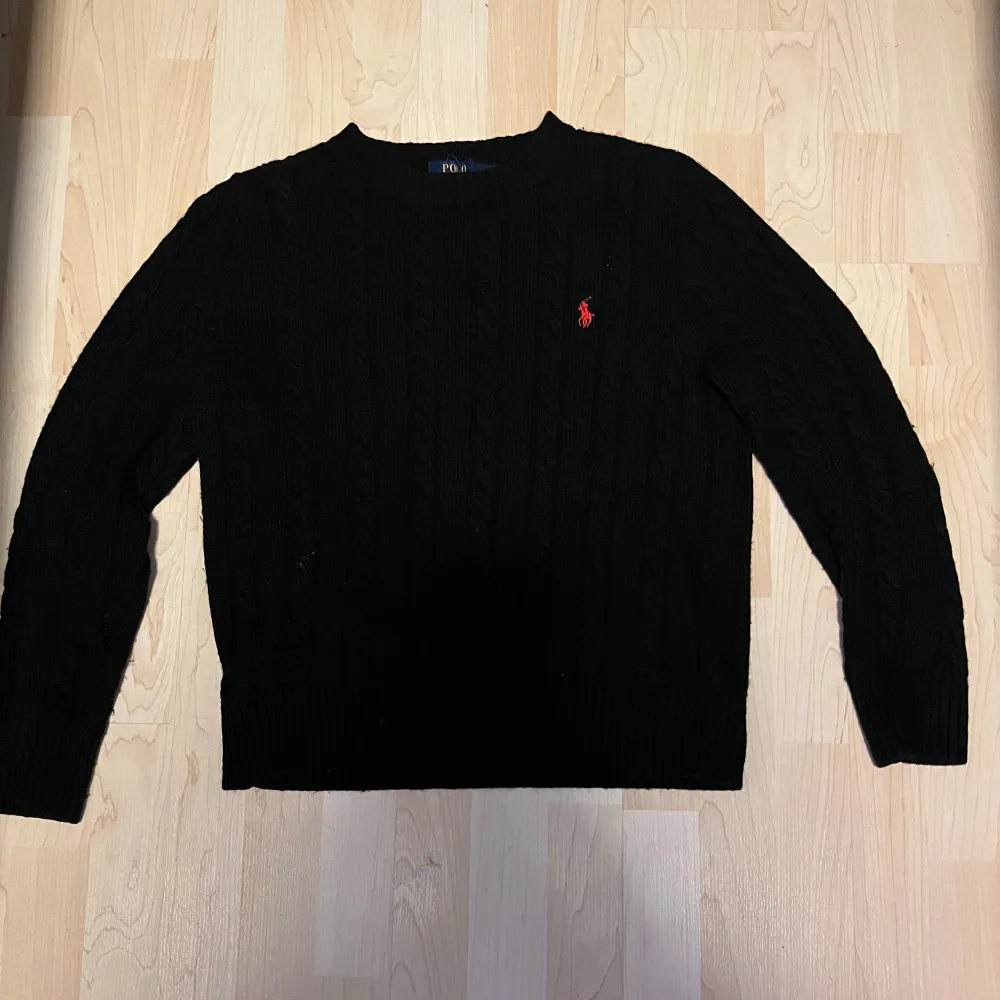 Säljer en klassisk svart stickad tröja från Polo Ralph Lauren. Den har en diskret röd logga på bröstet och är perfekt för både höst och vinter. Tröjan är i mycket bra skick och har långa ärmar. Perfekt för en bekväm stil. Tröjan är sparsamt använd och passar folk som är 170-180. . Tröjor & Koftor.