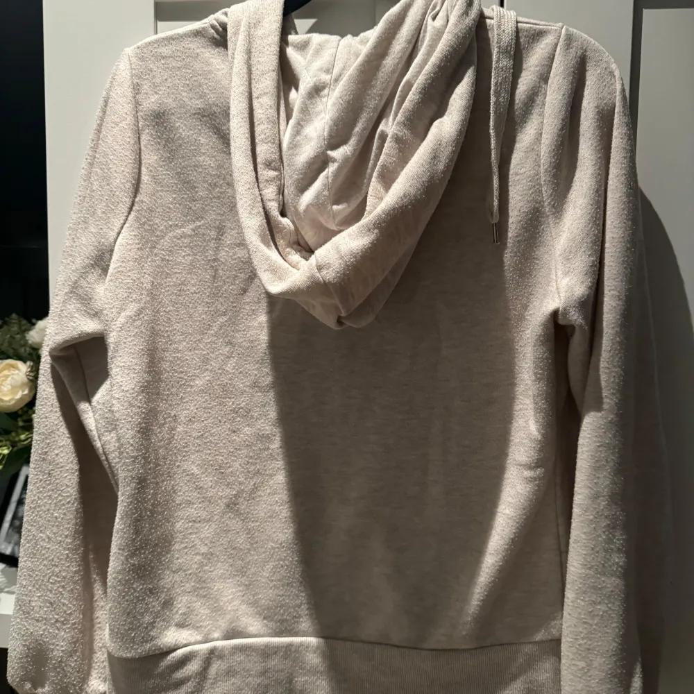 Mysig beige hoodie i mycket bra skick. Den har en praktisk dragkedja framtill och en stor huva med snören. Perfekt för kyliga dagar eller som ett extra lager under jackan. Den har också två fickor framtill för att värma händerna eller förvara småsaker.. Tröjor & Koftor.