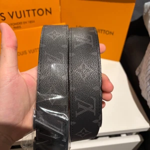 Svart bälte - Snyggt svart bälte med det klassiska monogrammönstret. Bältet har en stilren silverfärgad spänne  Perfekt för att ge en lyxig touch till din outfit.