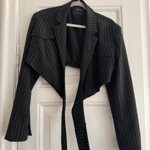 Cropped blazer - En croppad blazer som går runt midjan och knäpps fast i ryggan.