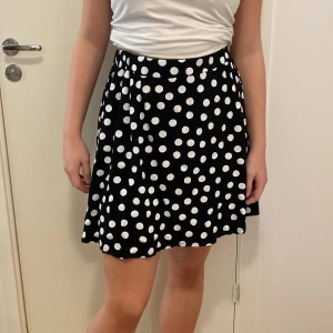 Svart prickig kjol från Black Story - Säljer en superfin svart kjol med vita prickar från Black Story. Kjolen är i storlek S och har en bekväm passform. Perfekt för både vardag och fest! 🖤