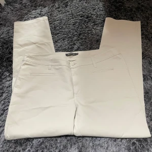 Beige byxor från Alice Bizous - Säljer ett par stilrena beige byxor från Alice Bizous i storlek 46. Byxorna har en klassisk design med raka ben och diskreta fickor. Perfekta för både vardag och festliga tillfällen. De är i nyskick och redo att bäras av någon som vill ha en tidlös look.