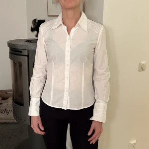 Figursydd skjorta - Figursydd skjorta med fina detaljer på axlarna och ärmarna. Från Mexx i strl 34 i fint skick