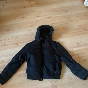 Svart jacka från Polo Ralph Lauren - Säljer en galet fet svart jacka från Polo Ralph Lauren. Den är perfekt för hösten men är även varm nog för vintern. Säljer den för att den inte används. Den är storlek 170 vilket motsvarar typ S eller XS. Inga defekter. Nypris 2550kr
