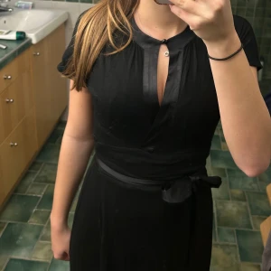 Klänning från Diane von Furstenberg! - Säljer en elegant svart klänning från Diane von Furstenberg i storlek S. Klänningen har en knytning i midjan och en fin detalj med satin vid halsen. Klänningen är ner till under knäna. Sömmarna längs armhålorna är lite utdragna. Perfekt för festliga tillfällen! 🖤