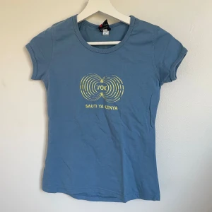 Blå t-shirt med tryck - Blå t-shirt i bomull med ett coolt tryck på framsidan som säger 'Sauti ya Kenya' vilket betyder ’voice of Kenya’. Den har korta ärmar och en normal passform. Perfekt för vardagsbruk eller sommarens äventyr! 💙 aldrig använd 