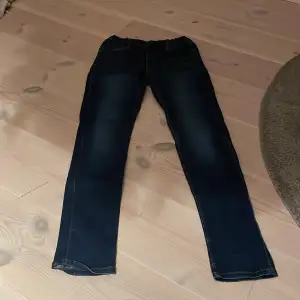 Säljer ett par mörkblå jeans från Name It i storlek 164. De har en klassisk straight passform och är perfekta för vardagsbruk. Jeansen är i bra skick och har en snygg tvätt som ger dem en cool look. Perfekta för både skola och fritid!