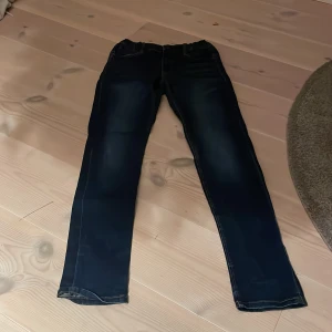 Mörkblå jeans från Name It - Säljer ett par mörkblå jeans från Name It i storlek 164. De har en klassisk straight passform och är perfekta för vardagsbruk. Jeansen är i bra skick och har en snygg tvätt som ger dem en cool look. Perfekta för både skola och fritid!