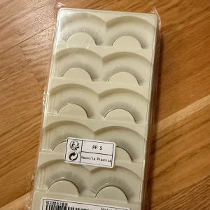 Falska ögonfransar i plastförpackning 30st - Säljer ett set med falska ögonfransar i en praktisk plastförpackning. Perfekta för att ge dina ögon en dramatisk look. Lätta att applicera och bekväma att bära hela dagen. Passar både till vardags och fest!