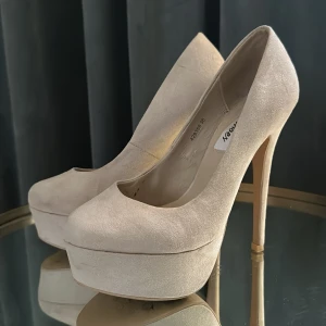Nelly Beige stilettklackar  - Nelly Beige stilettklackar med platå, Stl 36. Mockaimitation. Använda en gång. Lite märken på platåerna.