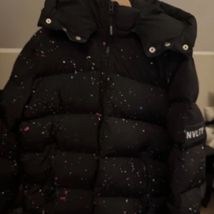 Svart pufferjacka från NVLTY - Säljer en svart pufferjacka från NVLTY i herrstorlek L. Perfekt för kalla dagar med sin tjocka vaddering och höga krage. Den har också en justerbar huva för extra skydd mot väder och vind. Topp skick och använd ca 1-2 gånger då min bror har gått ner i vikt så den är för stor för han. PRIS KAN DISKUTERAS VID SNABB AFFÄR.