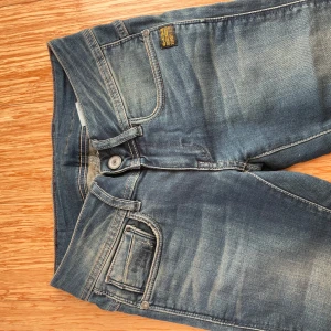 Blå jeans från G-Star - Säljer ett par snygga blå jeans från G-Star i storlek 32. De har en cool tvättad look och är i bra skick. Perfekta för vardagsbruk med en normal passform och klassisk design. Passar både till sneakers och kängor!