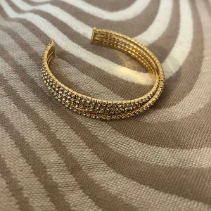 Guldarmband med glittriga stenar - Snyggt guldarmband  Armbandet är i nytt skick och har en elegant design som passar alla tillfällen.