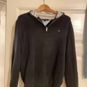 Svart tröja från Tommy Hilfiger - Säljer en stilren svart tröja från Tommy Hilfiger i mycket bra skick. Den har en dragkedja vid halsen och en logga på bröstet. Perfekt för både höst, vinter och vår. Skön passform och skönt material. Storlek Medium.