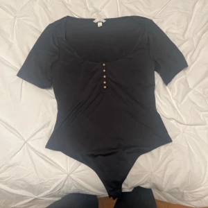 Svart bodysuit med knappar - Säljer denna body från H&M då den vart för stor för mig❤️helt ny utan prislapp