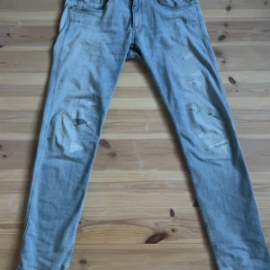 Ljusblå Replay Anbass - Säljer ett par ljusa Anbass från Replay i storlek 31. De har en snygg sliten look med hål på knäna och en tight passform. Perfekta för en avslappnad stil! 🕶️