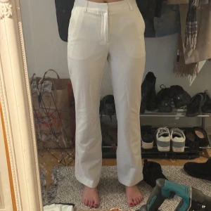 Vita kostymbyxor - Säljer ett par stilrena vita kostymbyxor i mycket bra skick. De är högmidjade och har en rak passform som ger en klassisk look. Perfekta för både kontoret och festligare tillfällen. Byxorna är gjorda i ett bekvämt material som känns skönt mot huden.