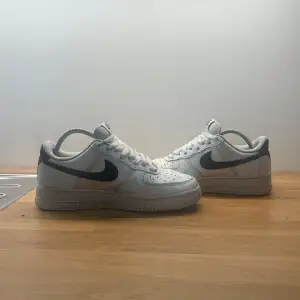 Säljer ett par klassiska Nike Air Force i vitt med svart swoosh. Skorna har snörning och är i bra skick. Perfekta för vardagsbruk och ger en stilren look.