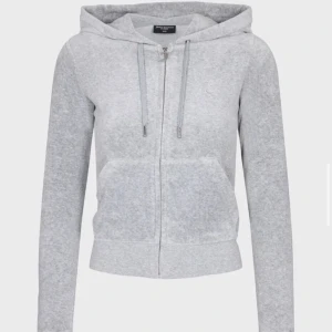 Grå hoodie från Juicy Couture - Säljer en supermjuk och bekväm grå hoodie från Juicy Couture. Perfekt för en avslappnad dag eller mysiga stunder hemma. Den har en dragkedja framtill och en klassisk huva med snören. Passar perfekt till jeans eller matchande mjukisbyxor. 🩶