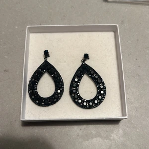 Svarta glittriga örhängen - Snygga svarta örhängen i droppform med glittriga detaljer. Perfekta för en festlig kväll eller en utekväll med vänner. De är lätta och bekväma att bära hela dagen. Ett måste för att ge din outfit det där lilla extra! ✨
