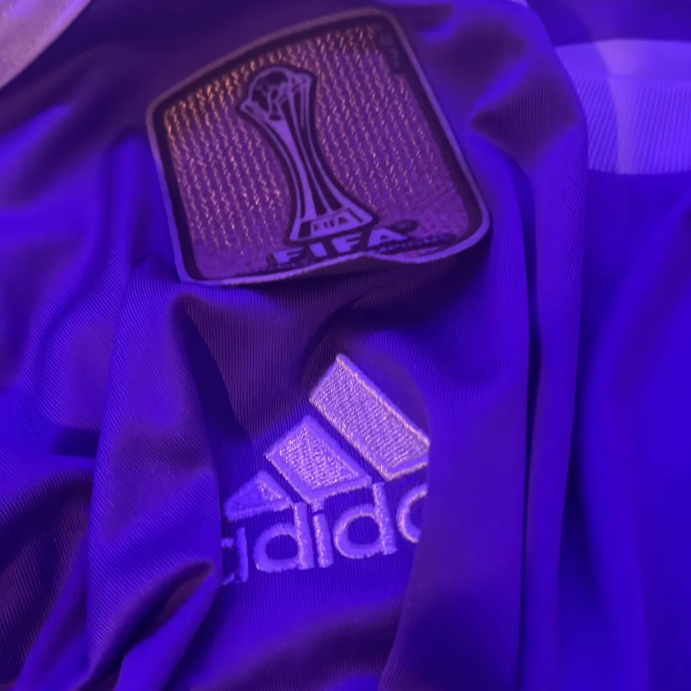 Säljer en snygg lila långärmad fotbollströja från Adidas med 'Fly Emirates' tryck och Real Madrid-emblem. Tröjan har vita detaljer och nummer 7 med 'Ronaldo' på ryggen. Perfekt för fans! 🌟. T-shirts.