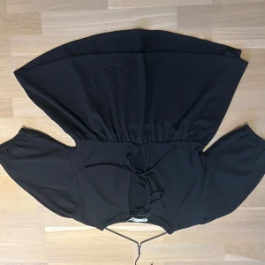 Svart blus med knyt - Säljer en svart blus med knyt. Den har korta ärmar och en luftig passform. Den är helt ny utan prislapp!