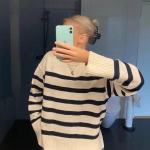 Randig tröja i bomull - Säljer en superfin randig tröja i bomull. Den är vit med marinblå ränder och har en avslappnad passform. Perfekt för både vår och höst! Tröjan har långa ärmar och ribbade muddar som ger en skön känsla. Passar perfekt till jeans eller kjol för en casual look.