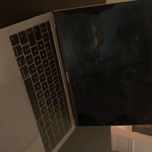 Grå MacBook pro - Säljer en stilren grå MacBook med ett unikt klistermärke på locket. Datorn är i gott skick och har en elegant design med en stor pekplatta och bakgrundsbelyst tangentbord. Perfekt för både arbete och nöje. Hör av dig vid intresse! Bra skick återställd