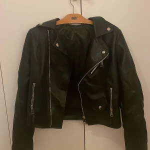 Svart skinnjacka - Säljer en snygg svart skinnjacka Den har coola dragkedjor och knappar som detaljer. Perfekt för höst och vår, och funkar lika bra till fest som till vardags. Jackan är i bra skick 💕