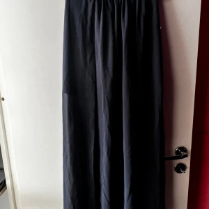 Svart långkjol från Bik Bok - Säljer en elegant svart långkjol från Bik Bok i storlek XS. Kjolen har en bekväm passform med dragkedja i midjan och är perfekt för både vardag och fest. Materialet är mjukt och faller fint, vilket ger en stilren look. Passar utmärkt till höst och vintergarderoben!